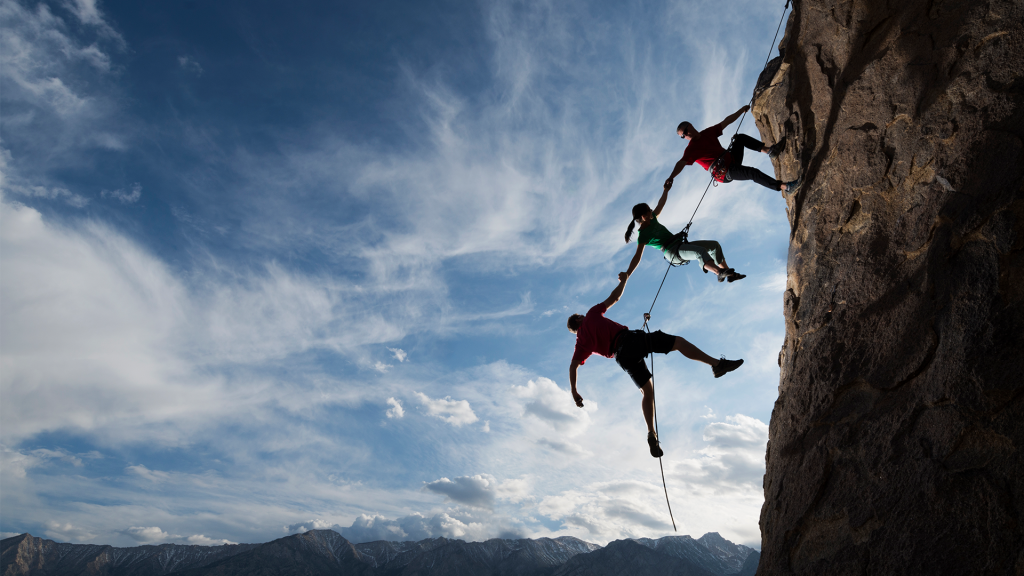 three rock climbers holding hands